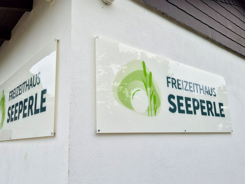 Zwei Schilder des Freizeithauses Seeperle hängen an einer Wand.