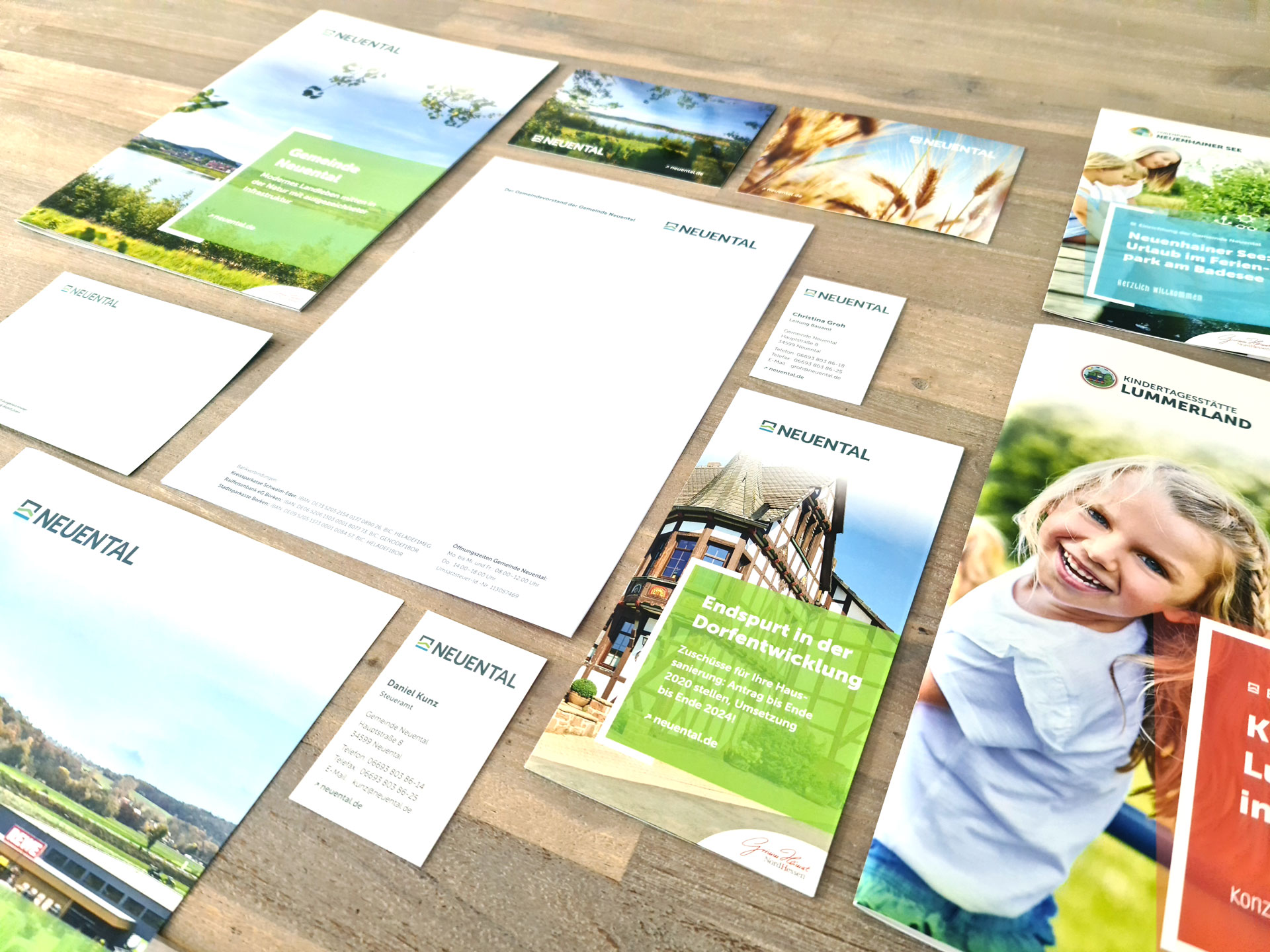 Verschiedene Printsachen der Gemeinde Neuental liegen ausgebreitet auf einem Holztisch