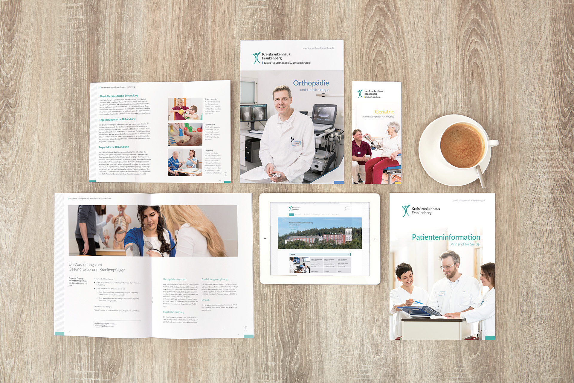 Auf einem Holztisch liegen Broschüren, Folder sowie ein Tablet mit der Webseite des Kreiskrankenhauses Frankenberg, daneben steht eine Tasse mit Kaffee.