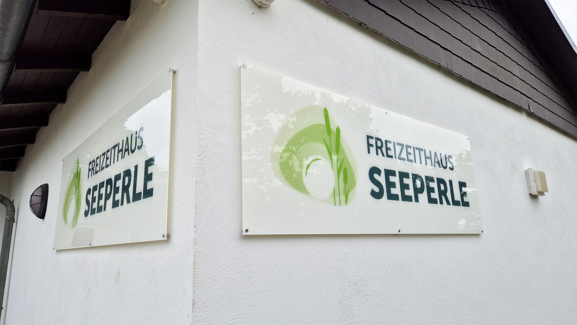 Zwei Schilder des Freizeithauses Seeperle hängen an einer Wand.