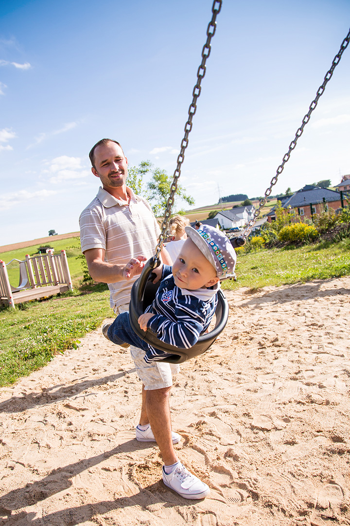 Ein Vater schubst sein Kind in einer Schaukel auf einem Spielplatz der Stadt Frankenberg an